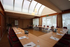 A conference room with a long table, red chairs, and a large window with curtains. - Best Western Hotel Rosenau (Bad Nauheim)