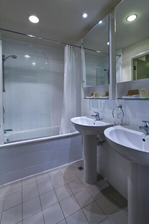 Une salle de bain moderne avec une douche à parois de verre, deux lavabos et un grand miroir.