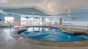 An indoor swimming pool with clear water, surrounded by a white fence, and equipped with multiple entry points and seating areas. - Quality Inn & Suites Fort Madison near Hwy 61 (Fort Madison)