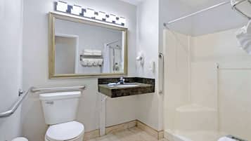 A bathroom with a toilet, sink, mirror, and shower.