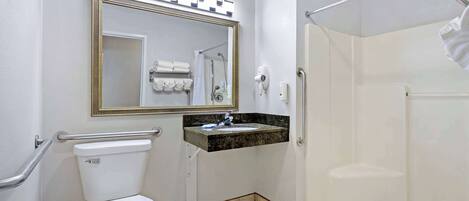 A bathroom with a toilet, sink, mirror, and shower.