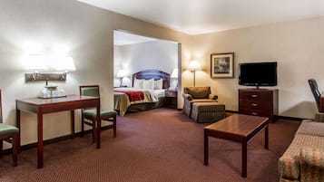 Quarto de hotel com cama, escrivaninha, poltrona, sofá, televisão e abajur.