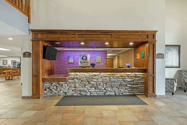 Un área de recepción con pared de piedra, mostrador de madera y un cartel que dice "Quality".