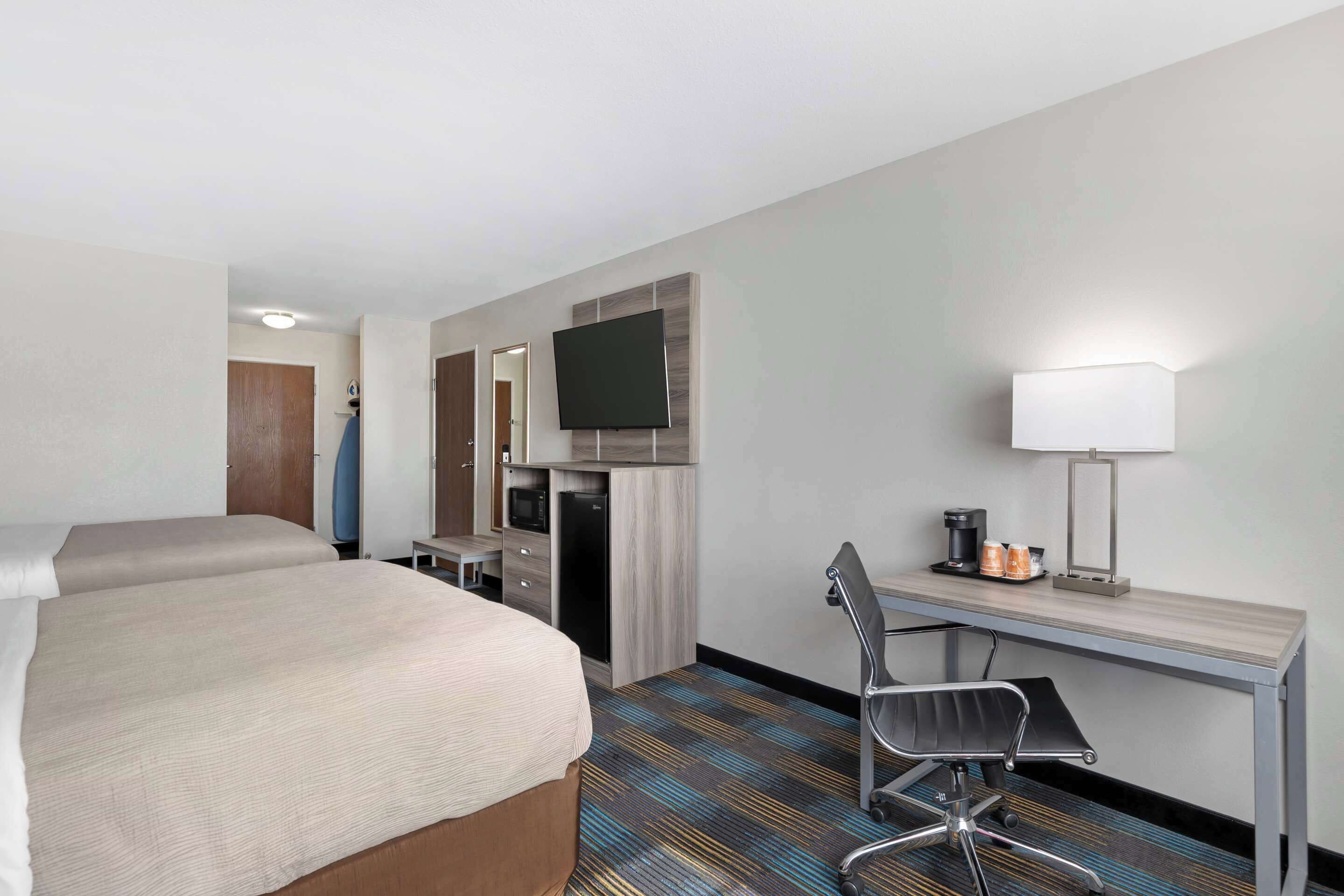 A hotel room with a large bed, a desk with a chair, a television, and a coffee maker.