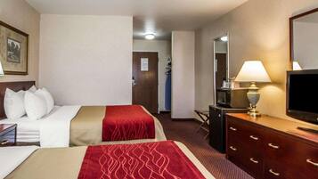 Una habitación de hotel con dos camas, un escritorio con lámpara, televisión y cómoda.
