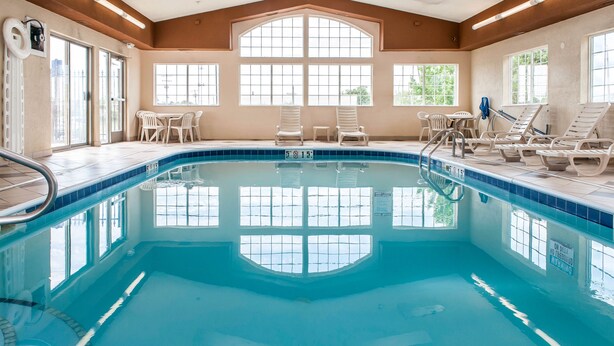 Une piscine intérieure à l’eau claire, dont la profondeur est indiquée à 3 pieds, et qui est entourée de plusieurs chaises longues.