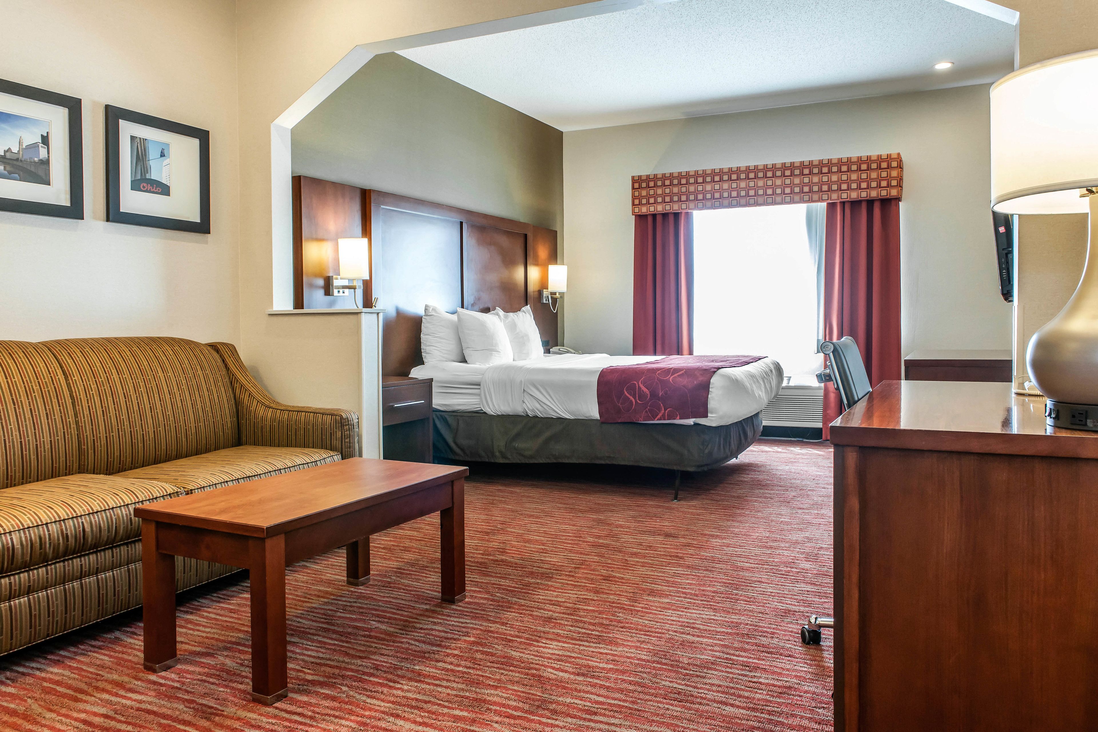 Una habitación de hotel con cama, sofá, escritorio y lámpara.