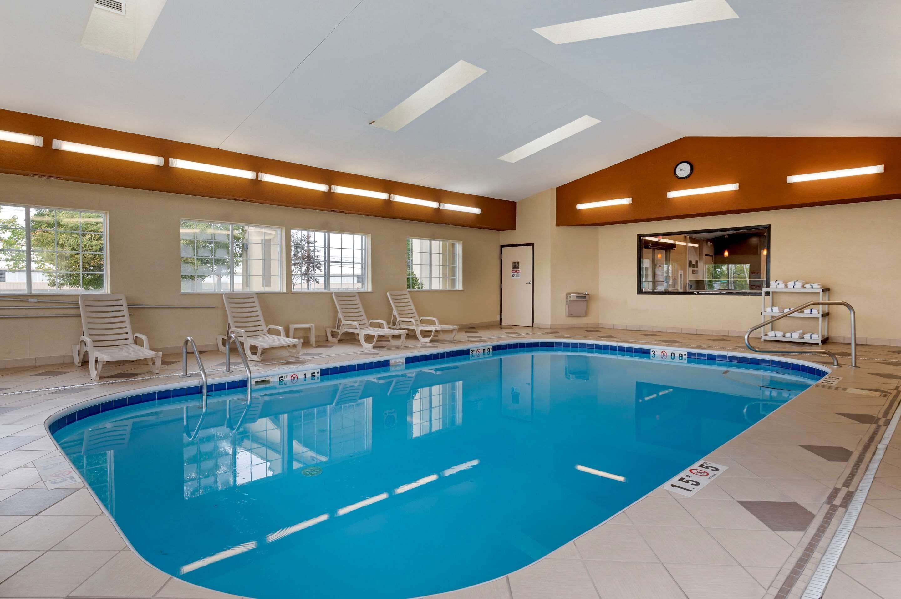 A swimming pool with lounge chairs and a sunroof.