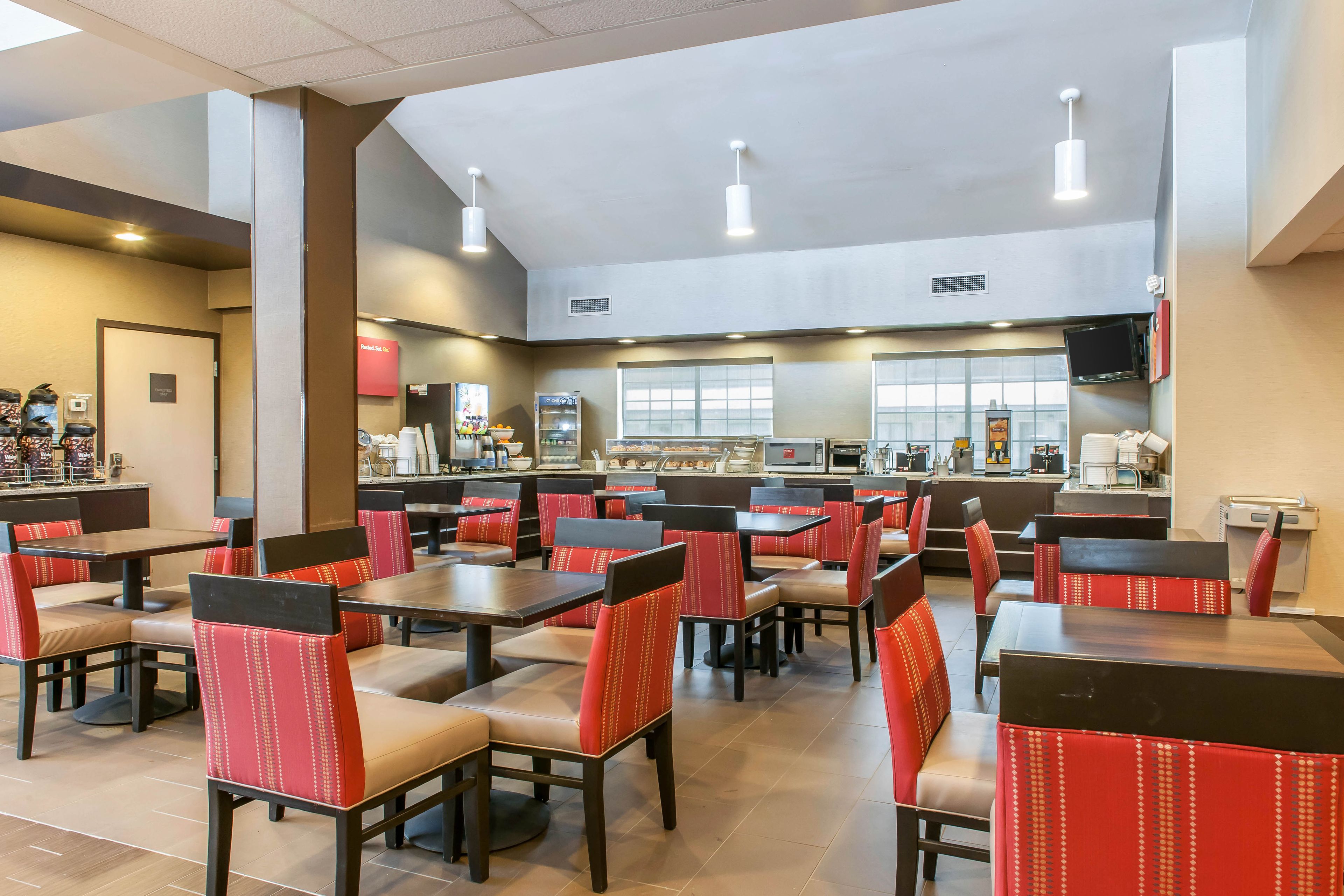 A spacious restaurant with multiple tables and booths, featuring a modern design with red and beige seating.