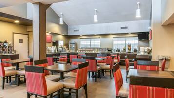A spacious restaurant with multiple tables and booths, featuring a modern design with red and beige seating.