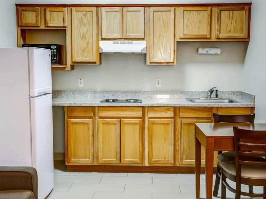 A compact kitchen with wooden cabinets, a built-in microwave, a stove, and a sink.