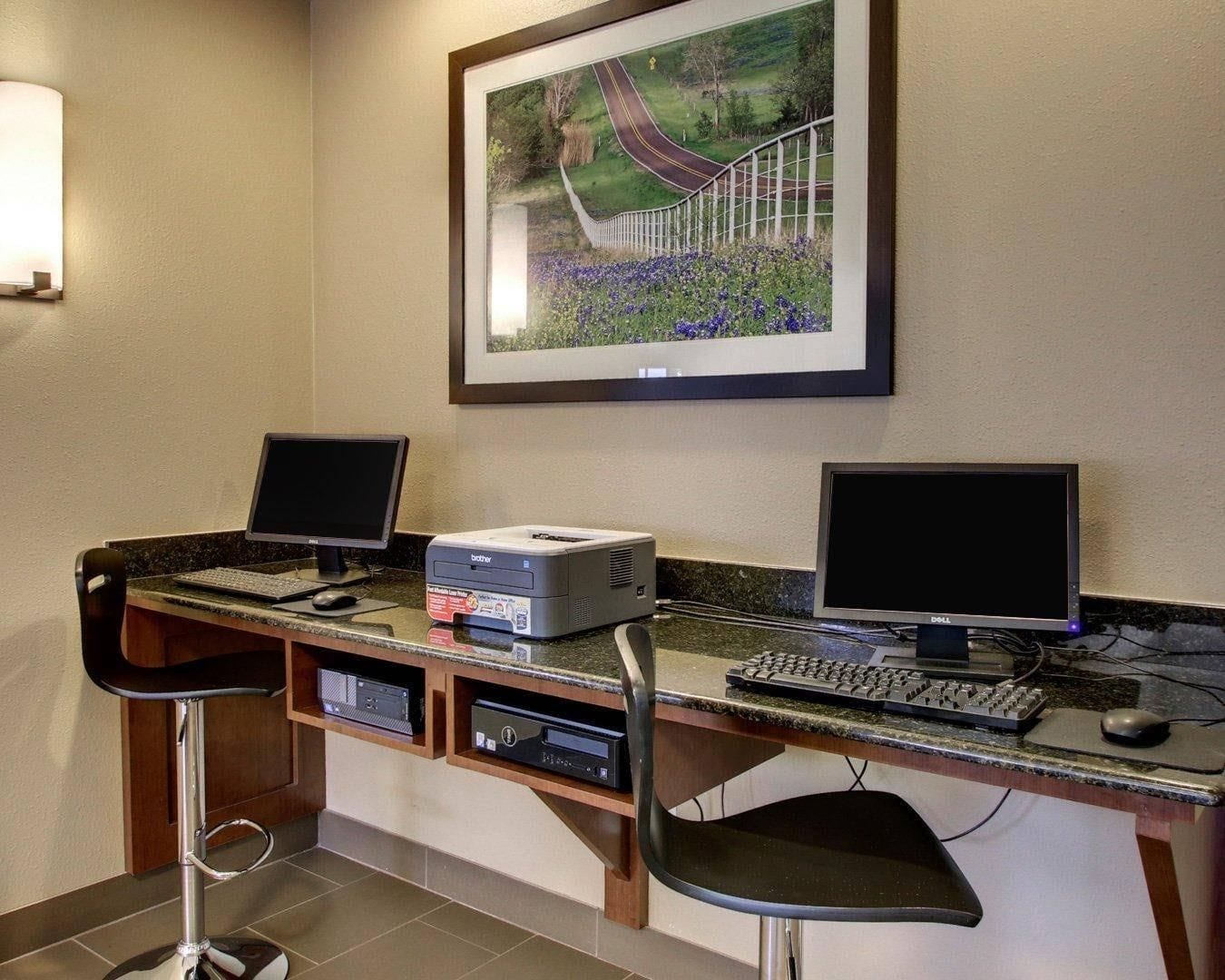 A workspace with two monitors, a printer, and a keyboard.