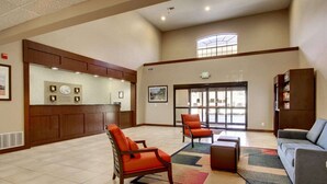 A spacious lobby with a reception desk, seating area, and a large window providing natural light.
