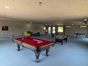 A recreational room with a pool table, foosball table, and several chairs. - Comfort Suites Tyler South (Tyler)