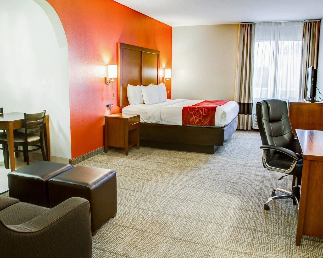 Una camera d'albergo con un letto, comodini, una scrivania, una sedia e un piccolo angolo salotto.