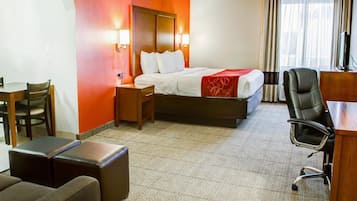 Habitación de hotel con cama, mesitas de noche, escritorio, una silla y un pequeño rincón de descanso.