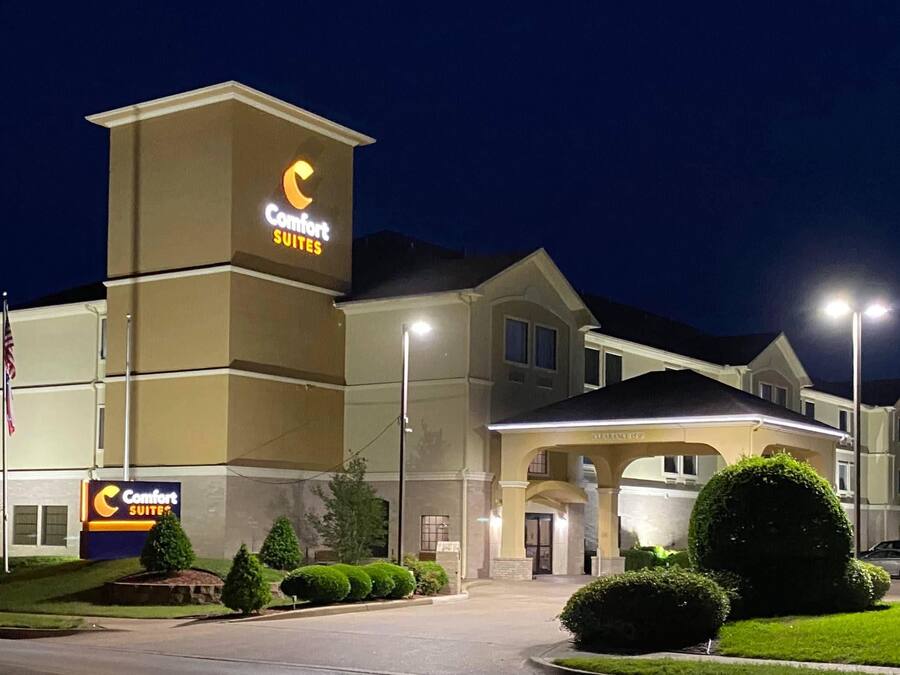 Un hotel Comfort Suites con un cartel llamativo, entrada cubierta y jardines bien cuidados.