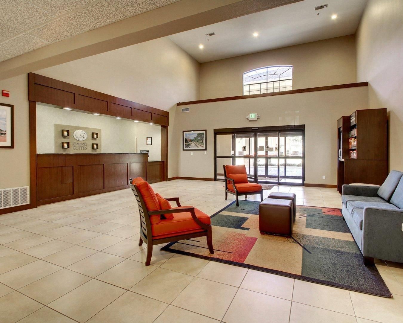 A hotel lobby with a reception desk, seating area, and a large window.