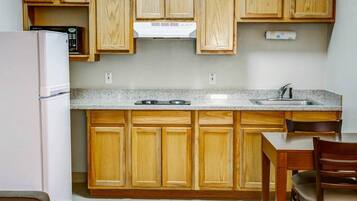 A kitchen with wooden cabinets, a refrigerator, a microwave, a stove, and a sink.