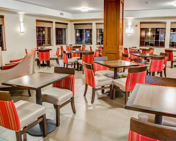 Un restaurant doté de nombreuses tables et chaises, d’un pilier en bois et de grandes fenêtres.