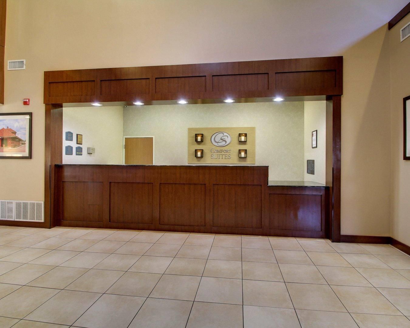 Una reception con finitura in legno, un cartello sopra e un pavimento piastrellato.