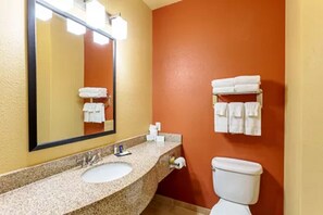 A bathroom with a sink, mirror, and toilet. There are towels hanging on the wall. - Comfort Suites Tyler South (Tyler)