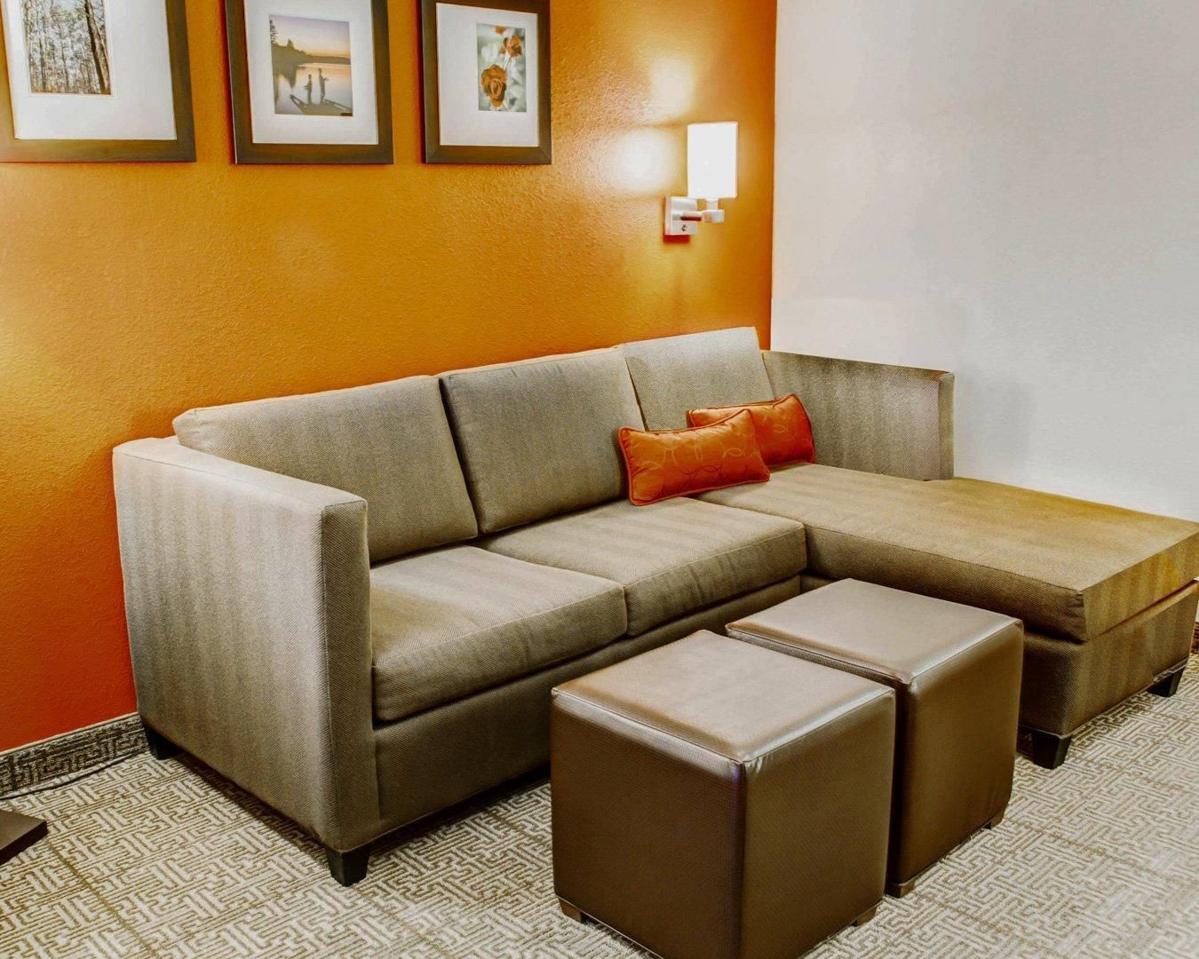 A sectional sofa with a chaise, a patterned rug, and a wall-mounted light fixture.