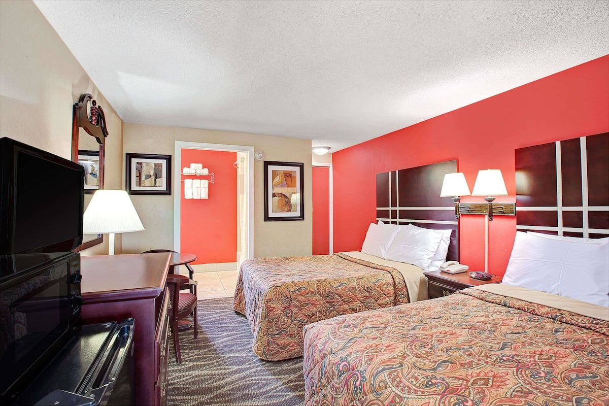 Une chambre d’hôtel avec deux lits, une télévision, un bureau et une chaise.