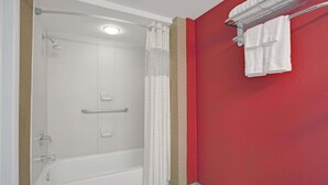 A bathroom with a white bathtub, a shower, and a red wall. - Days Inn by Wyndham Ridgefield NJ (Ridgefield)
