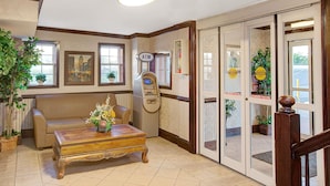 A lobby with a sofa, a coffee table, an ATM, and a door with a sign. - Days Inn by Wyndham Ridgefield NJ (Ridgefield)