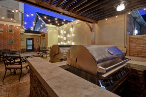 An outdoor patio with a grill, tables, chairs, and string lights. - Homewood Suites By Hilton Houston IAH Airport Beltway 8 (Houston)