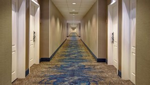 Un pasillo de hotel con pisos alfombrados, puertas a ambos lados y un techo con iluminación empotrada.