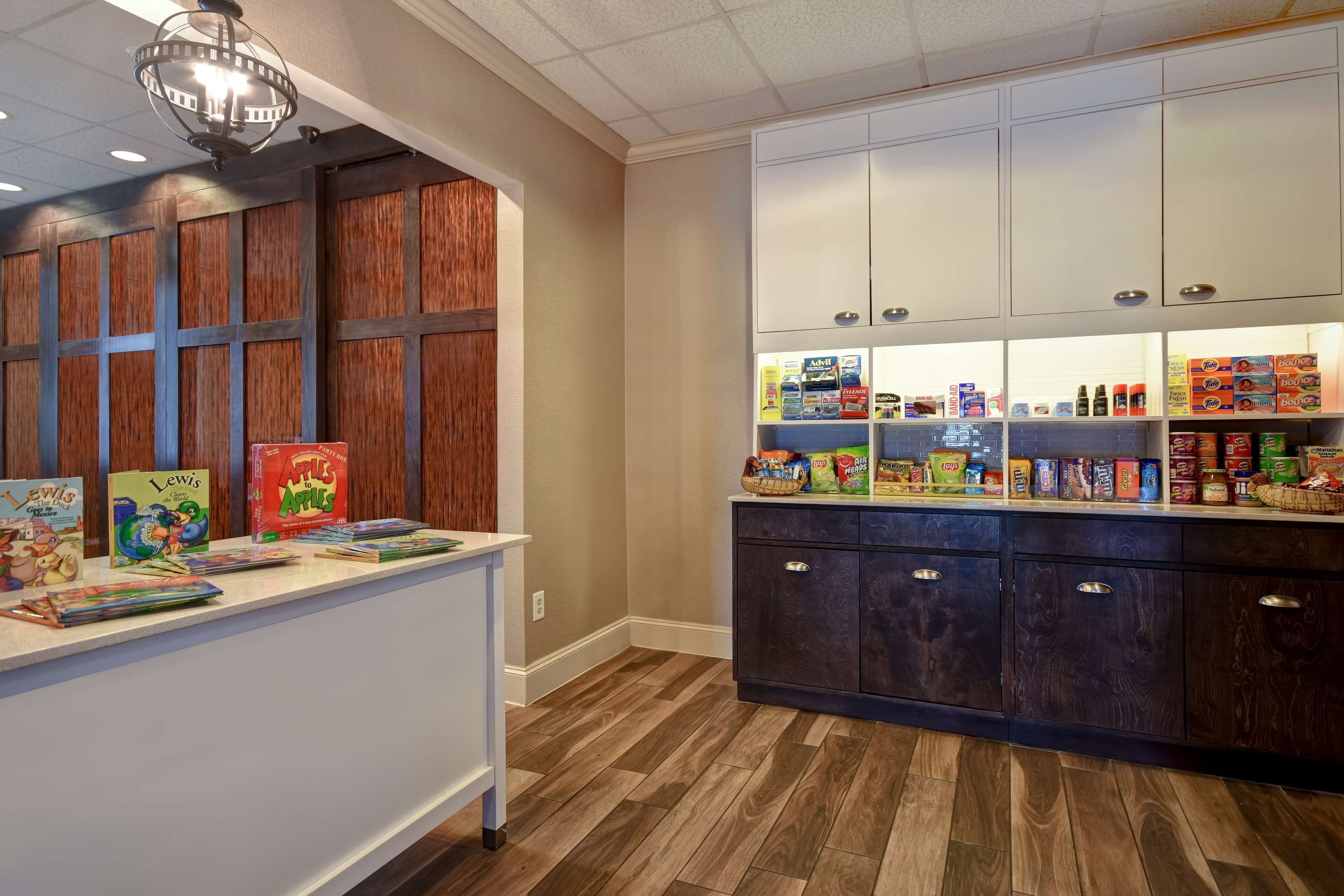 A kitchen area with wooden cabinets, a white countertop, and various food items.