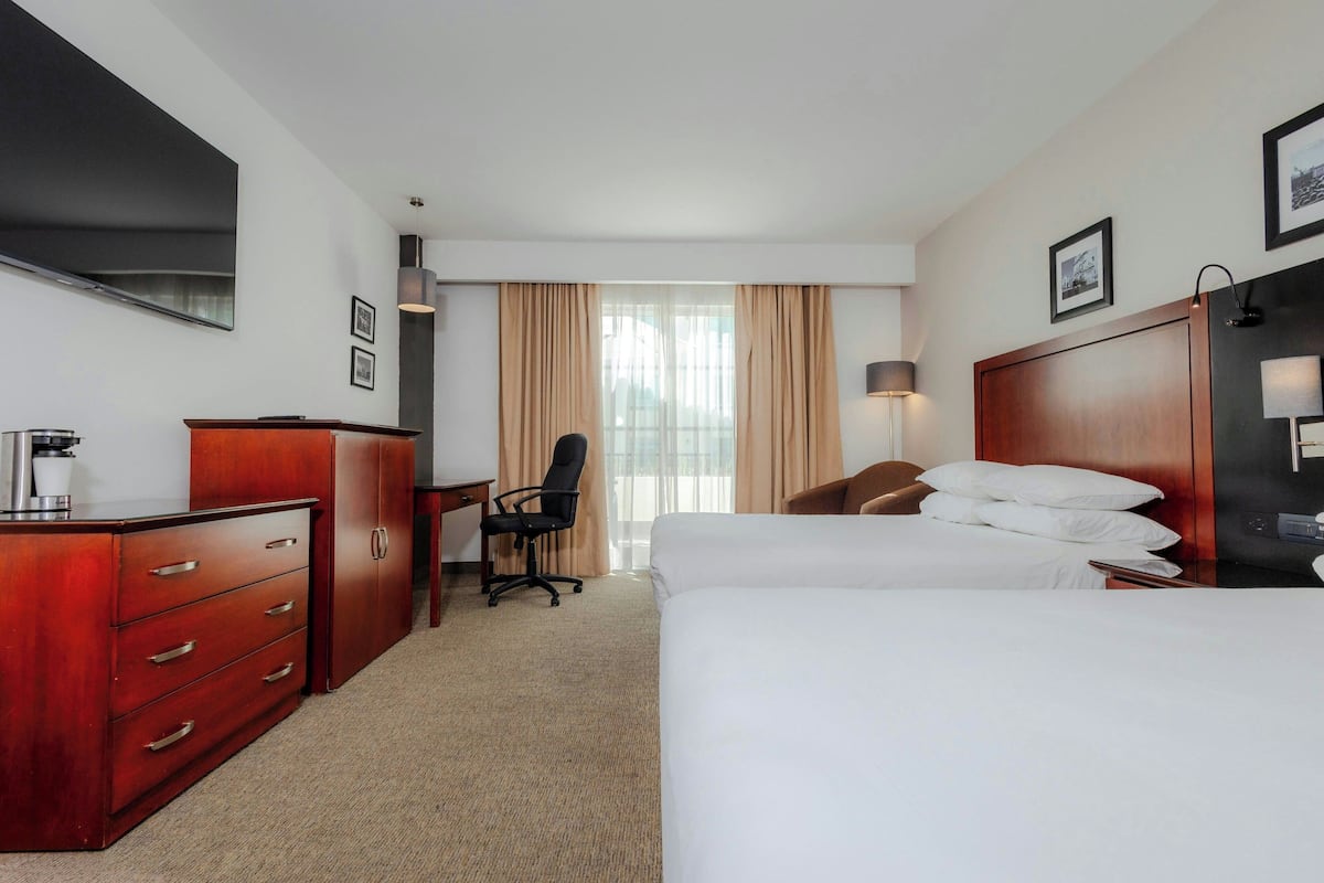 Una habitación de hotel con cama, escritorio, silla, cómoda y televisor.