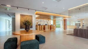 Un hall espacioso con mostrador de recepción, zona de estar y un cuadro abstracto de gran tamaño.