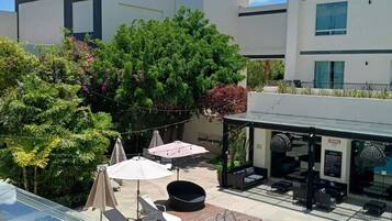A modern hotel with a swimming pool, outdoor seating, and a covered area with umbrellas.