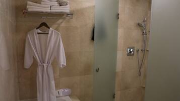 A bathroom with a bathtub, a shower, and a towel rack with folded towels.