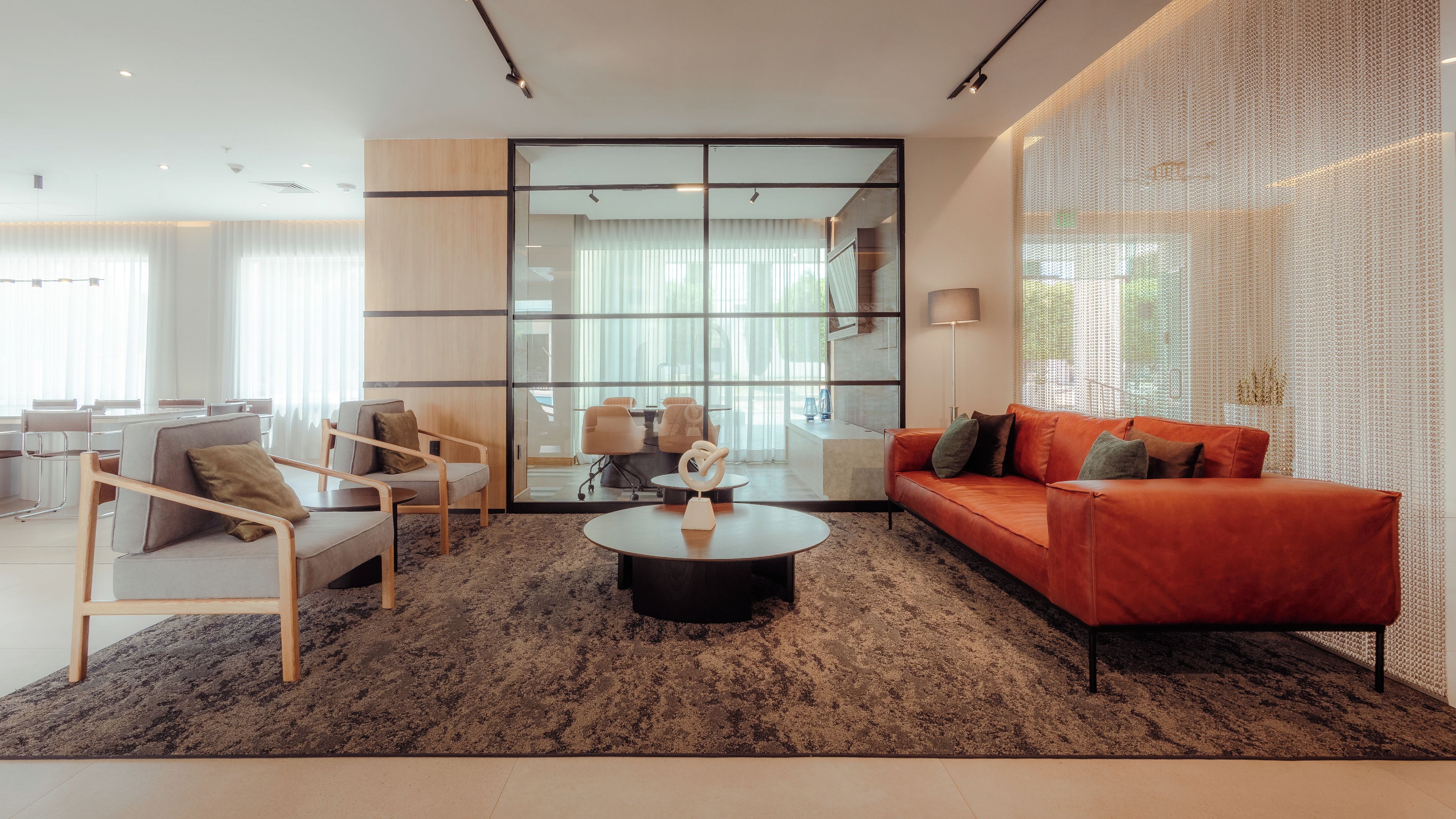 Una sala de estar moderna con un sofá, sillas, una mesa de centro y un ventanal grande.