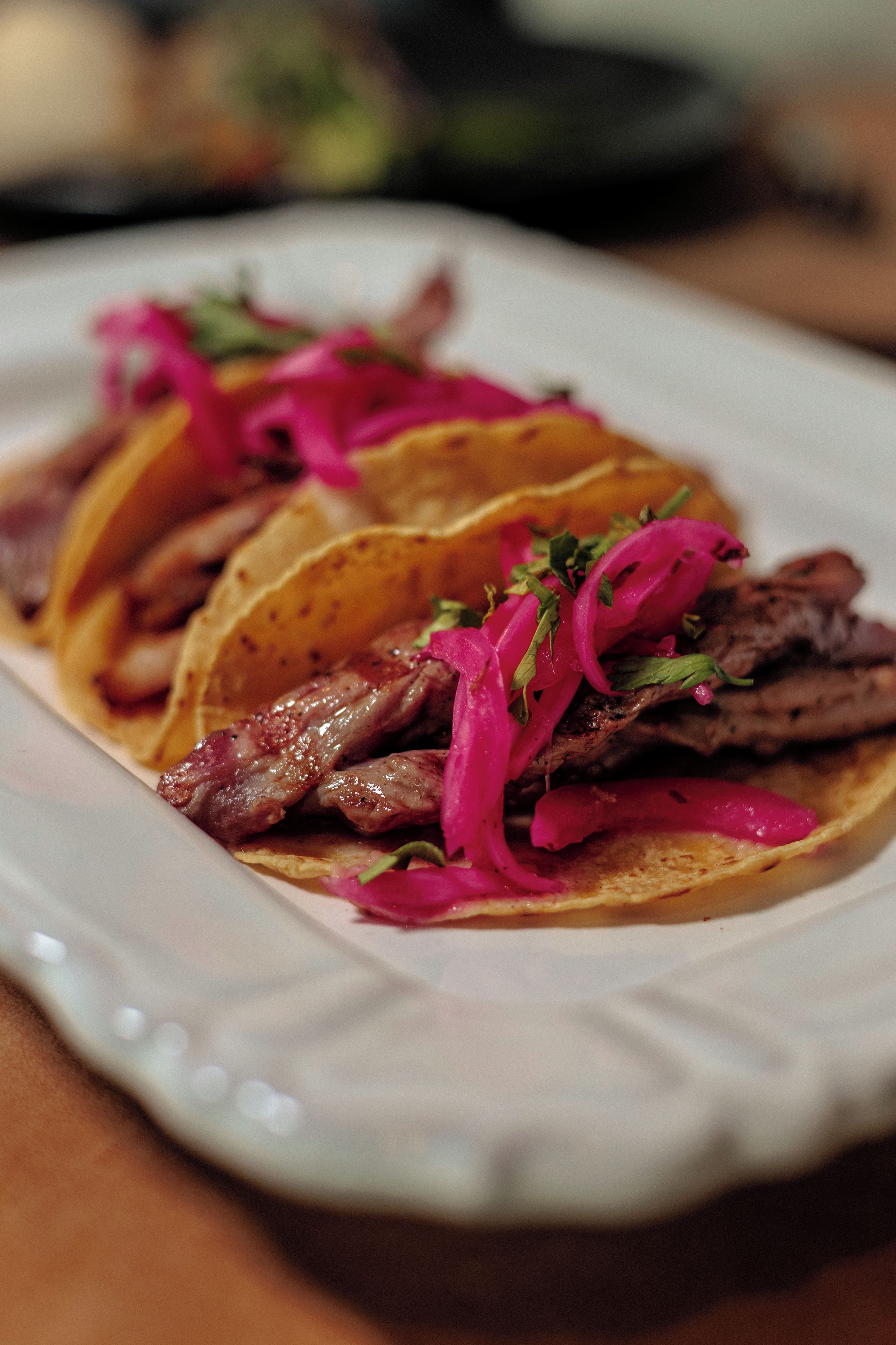 Un plato de tacos con carne y cebollas rojas.