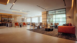 A modern hotel lobby with a bar area, seating arrangements, and large windows. - Sheraton Leon (León)