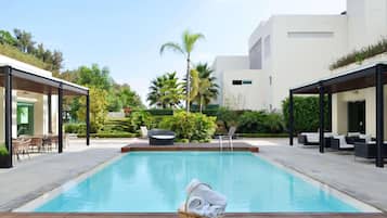 Una piscina al aire libre, sillones reclinables de piscina