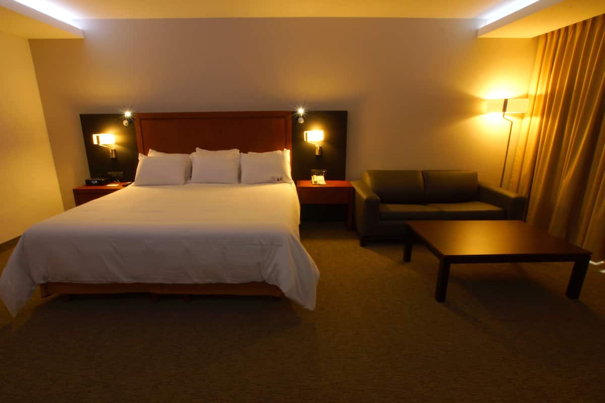 Ein Hotelzimmer mit einem großen Bett, einer Couch, einem kleinen Tisch und zwei Nachttischen mit Lampen.