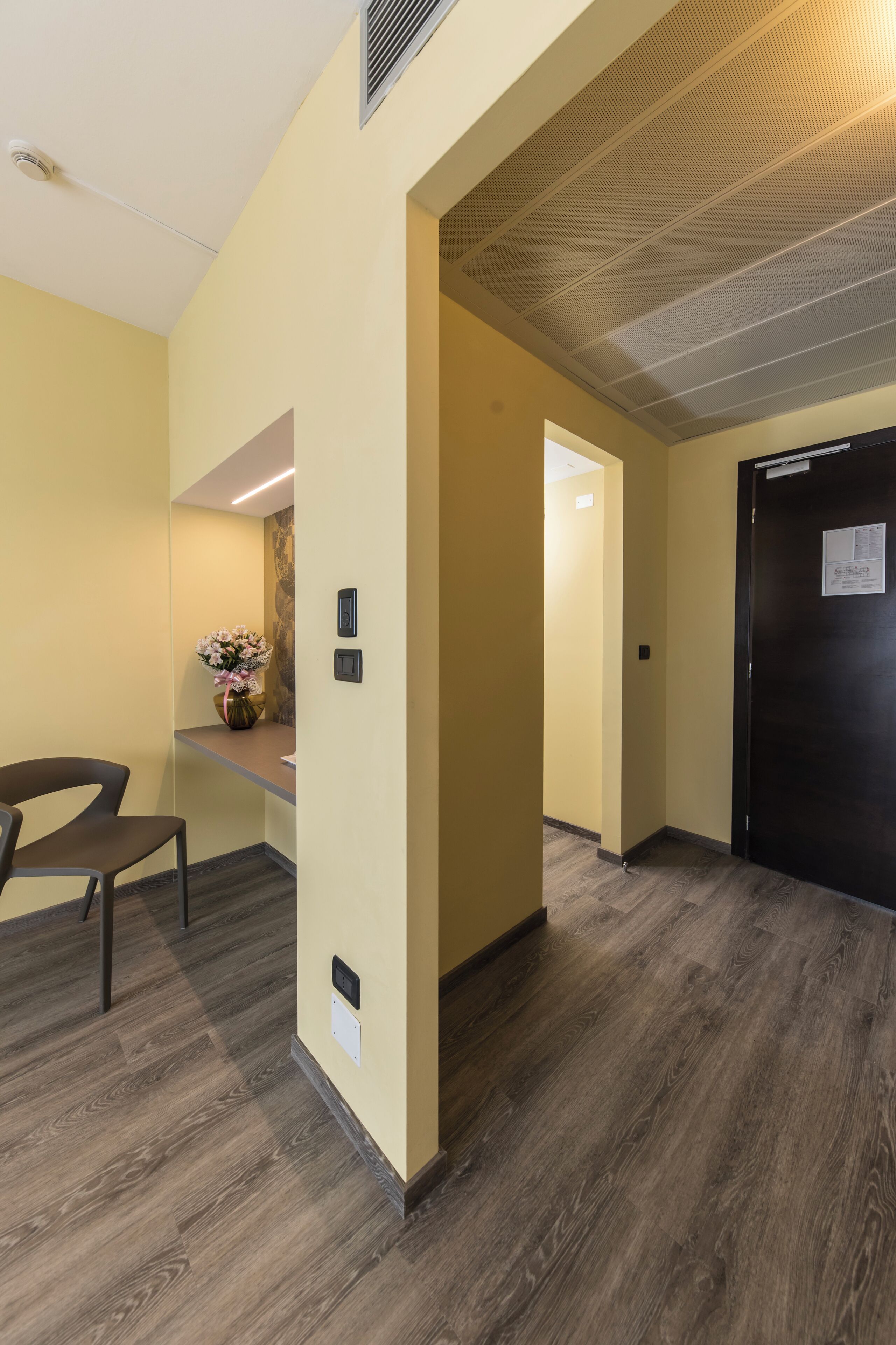 A hallway with wooden flooring, a reception desk, and a black door.