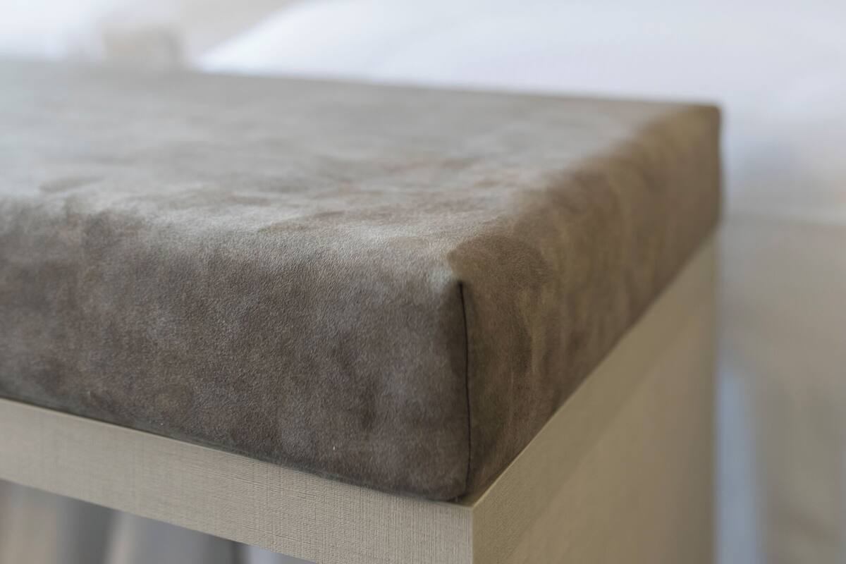 A bed with a grey headboard and white bedding.