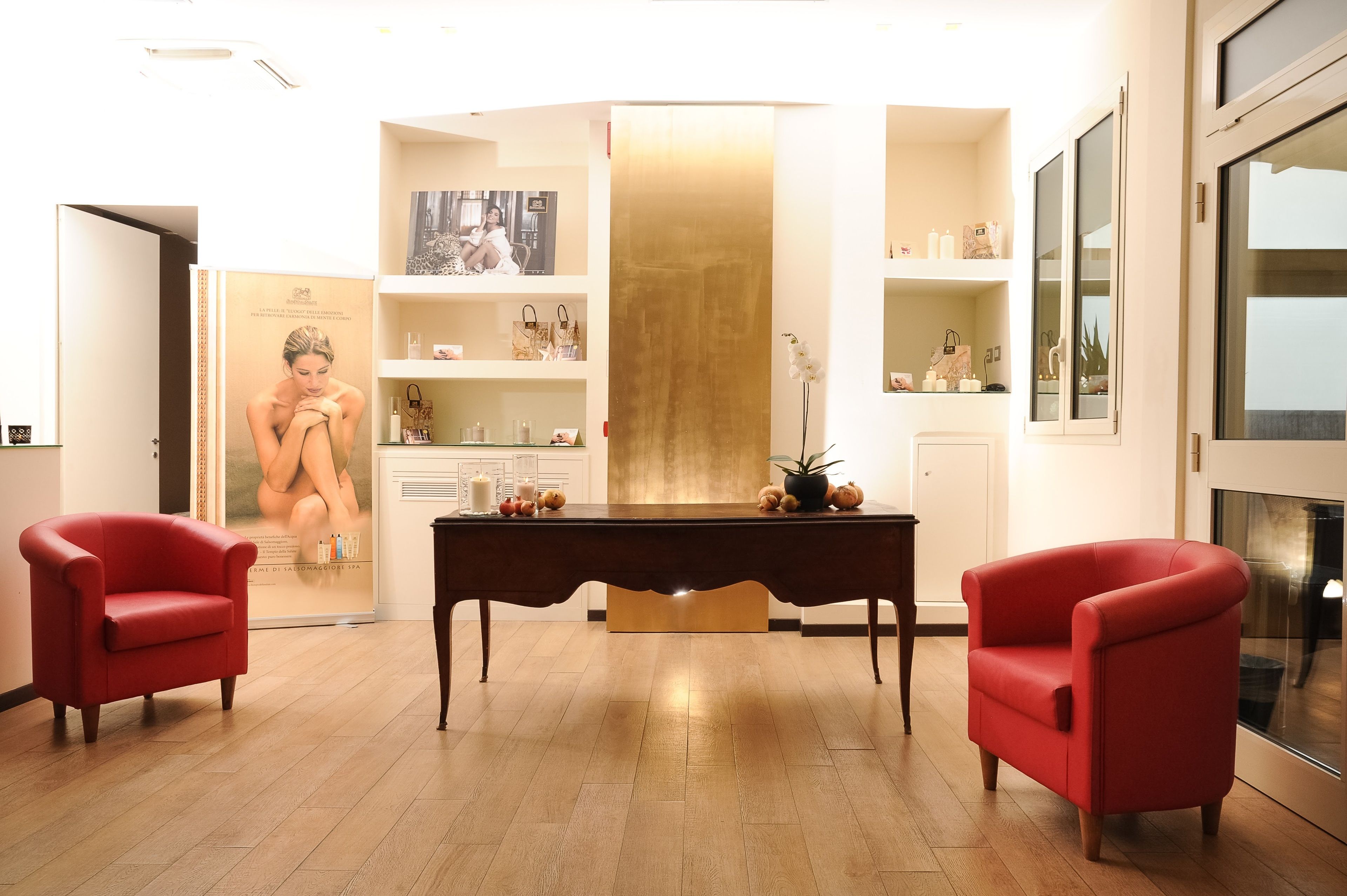 Un interior moderno con suelo de madera, una mesa central y dos sillones rojos.