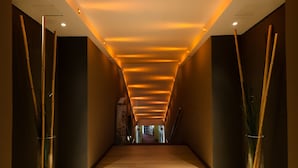 Un pasillo moderno con suelo de madera, paredes oscuras e iluminación empotrada en el techo.