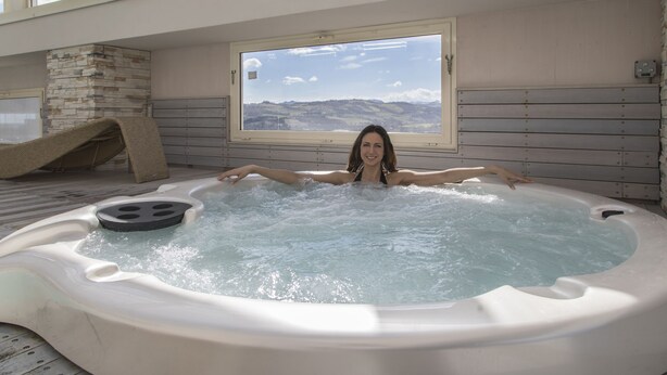Un jacuzzi con vistas a las montañas a través de un ventanal grande.