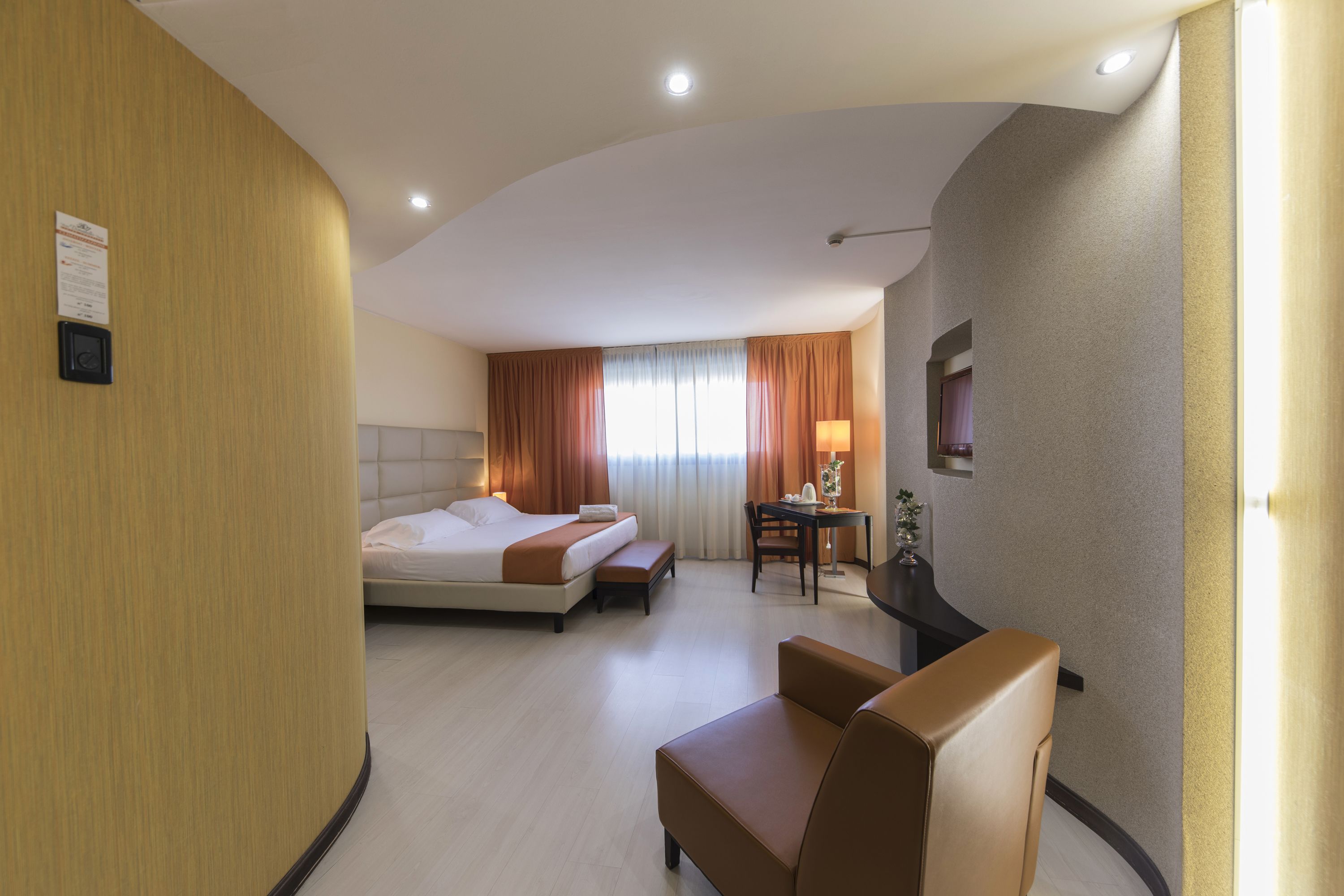 Una habitación de hotel con una cama, un escritorio, una silla y una mesita de noche con lámpara.