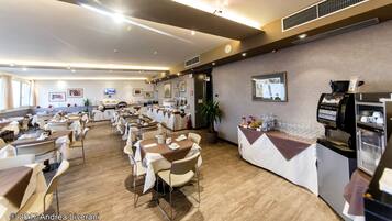 A spacious dining area with multiple tables and chairs, a coffee machine, and a buffet counter.