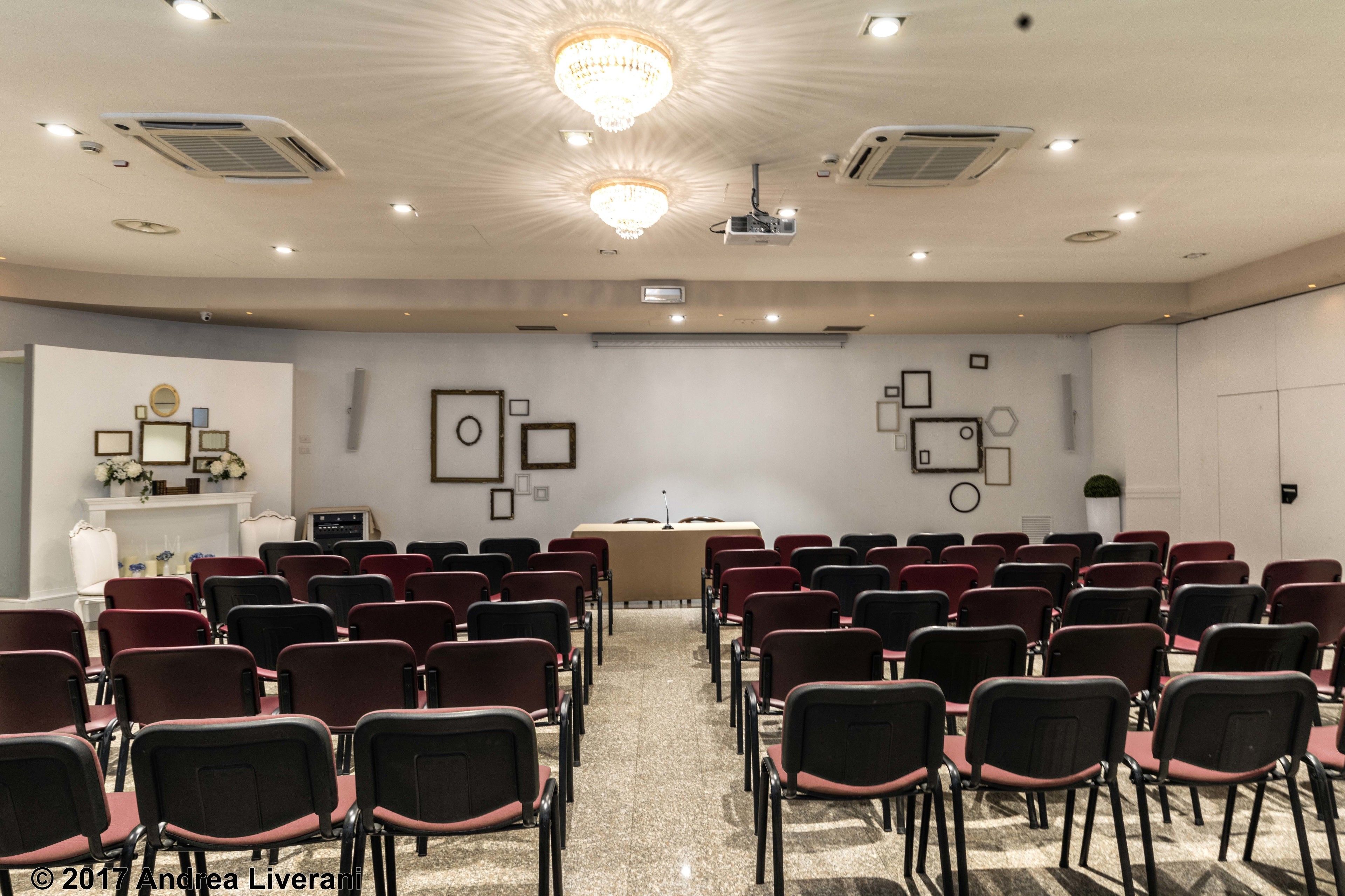 Un salón de conferencias con filas de sillas, un atril y un proyector.